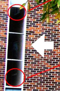 The altered photo, enhancing CONTRAST ONLY, to make out the image clearly: what, other than the adjacent window frames, appears in this reflection?